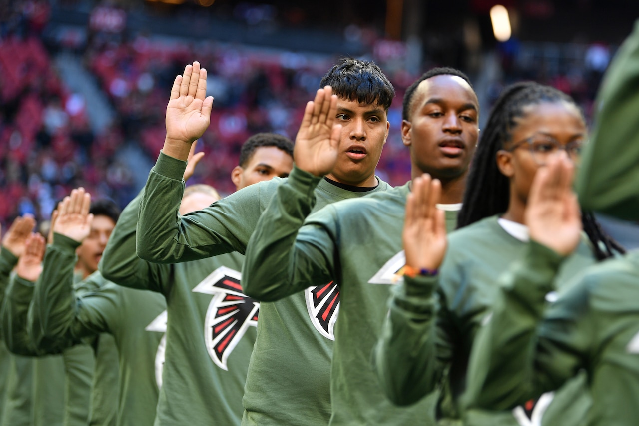 People standing in a row raise their right hands.