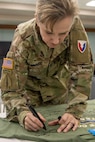 Brig. Gen. Paige M. Jennings, U.S. Army Financial Management Command commanding general, signs a commemorative shirt shortly after a ceremony reactivating the 45th Finance Center at the Maj. Gen. Emmett J. Bean Federal Center in Indianapolis Nov. 6, 2023. The 45th FC draws its legacy back to World War II when the unit was first activated as the 45th Finance Disbursing Section on Fort Benjamin Harrison in Indianapolis in 1943 – nearly in the exact location where it was reactivated 80 years later. (U.S. Army photo by Mark R. W. Orders-Woempner)