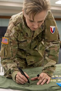 Brig. Gen. Paige M. Jennings, U.S. Army Financial Management Command commanding general, signs a commemorative shirt shortly after a ceremony reactivating the 45th Finance Center at the Maj. Gen. Emmett J. Bean Federal Center in Indianapolis Nov. 6, 2023. The 45th FC draws its legacy back to World War II when the unit was first activated as the 45th Finance Disbursing Section on Fort Benjamin Harrison in Indianapolis in 1943 – nearly in the exact location where it was reactivated 80 years later. (U.S. Army photo by Mark R. W. Orders-Woempner)