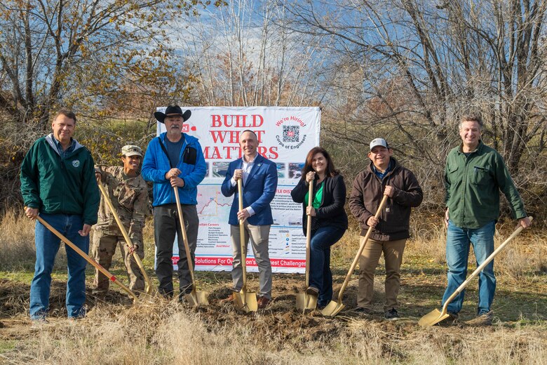 A group of people holding golden shovels about to break ground on a new project.