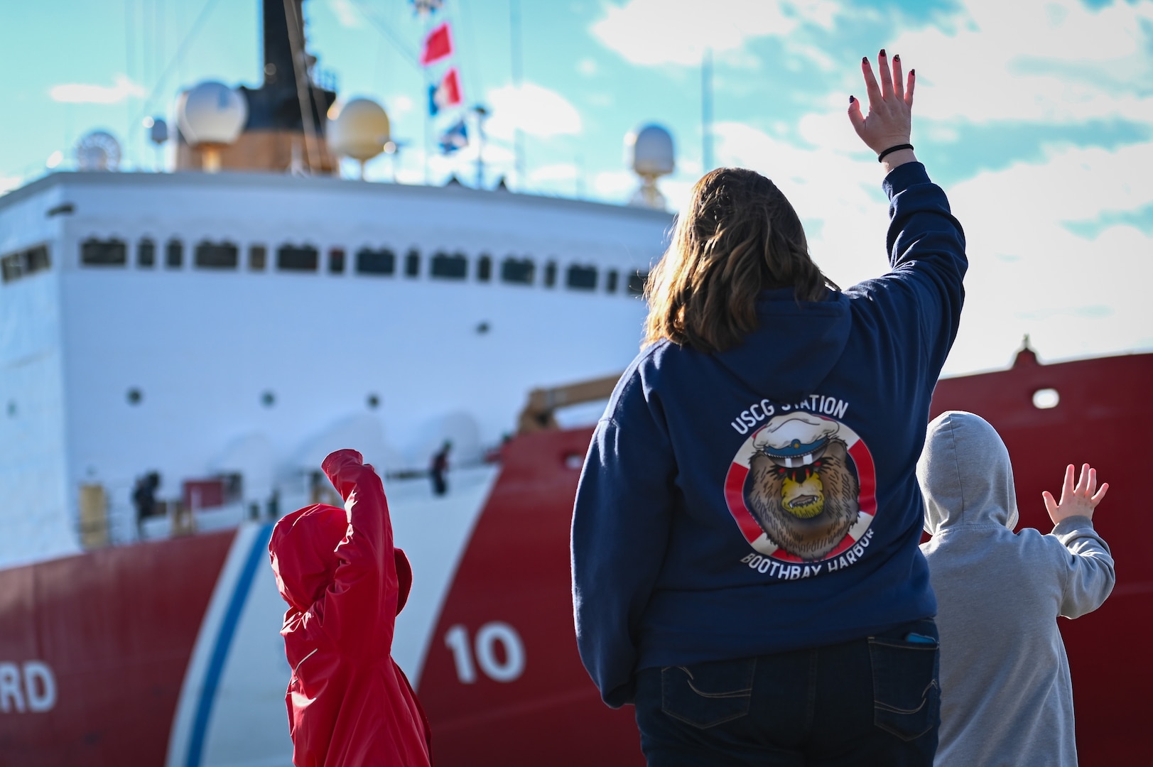 Family members wave to the crew aboard U.S. Coast Guard Cutter Polar Star (WAGB 10) as the vessel begins to push away from the pier at Base Seattle on Nov. 15, 2023. The crew of the Polar Star are beginning their voyage to Antarctica in support Operation Deep Freeze, the annual joint military mission to resupply the United States Antarctic stations. (U.S. Coast Guard photo by Petty Officer Steve Strohmaier)