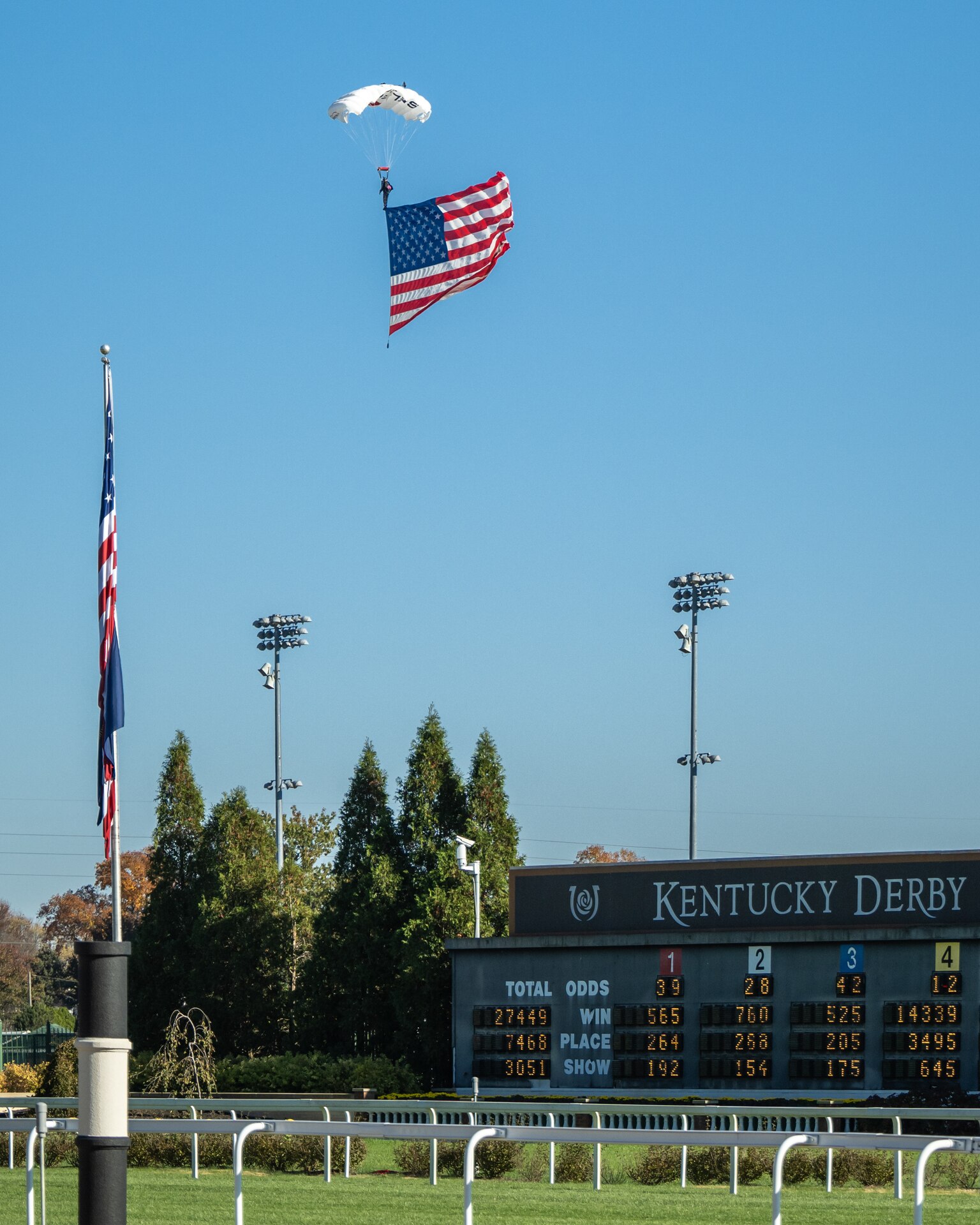 A parachutists skydives into Churchill Downs Racetrack in Louisville, Ky., Nov. 5, 2023, with a U.S. flag as part of Survivor’s Day at the Races, an annual event to honor family members who've lost loved ones in military service to the United States. Hosted with assistance from the Kentucky National Guard, the event drew more than 700 family members from 18 states. (U.S. Air National Guard photo bay Dale Greer)