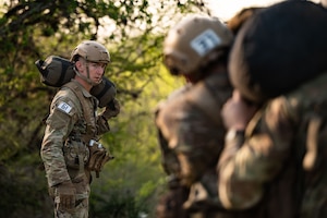 man in uniform turns around to look at group carrying weighted log