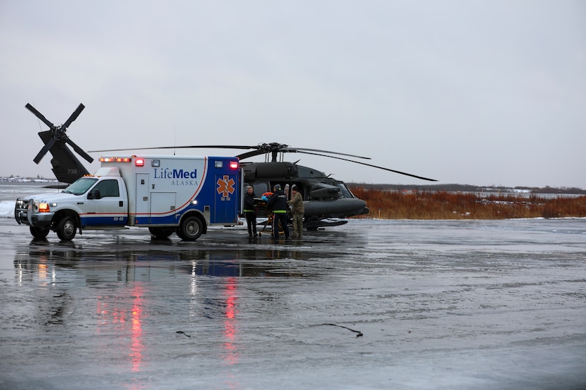 From the left, Holly Demert and Clifton Dalton, both flight paramedics with LifeMed, and Chief Warrant Officer 3 Bryan Kruse, Bethel Army Aviation Operating Facility commander, move a critically ill patient from an AKARNG UH-60L Black Hawk helicopter to an ambulance during a medical evacuation from Napaskiak to Bethel, Nov. 15, 2023