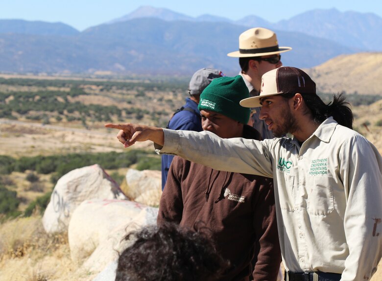Victor Gonzales, 21, San Bernardino, foreground, and Joe Taylor, 19, San Bernardino, both with the Urban Conservation Corps of the Inland Empire, under the umbrella of the Southern California Mountains Foundation point out a feature at the Mojave River Dam Oct. 17 in Hesperia, California.