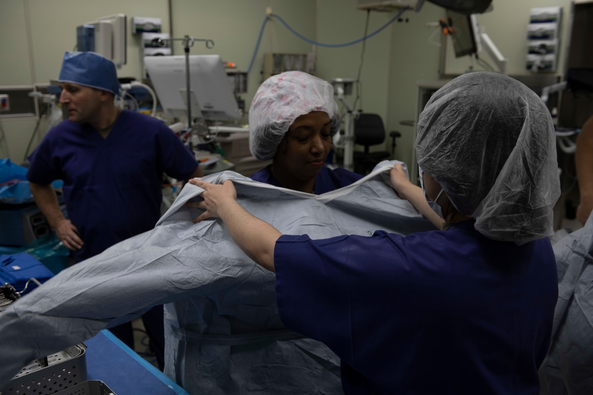 A military member puts on a surgical apron during a tour