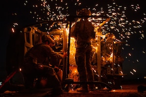 A U.S. Air Force quick reaction force member assigned to the 409th Expeditionary Security Forces Squadron helps a rescue specialist cut apart a vehicle