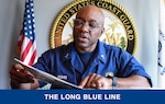 Chief Warrant Officer Kristopher McGhee reviews a scrapbook of milestones in his career in a conference room at Base Seattle, July 17, 2023. McGhee served in the health services field in the Coast Guard for over 30 years. U.S. Coast Guard photo by Petty Officer 3rd Class Annika Hirschler.