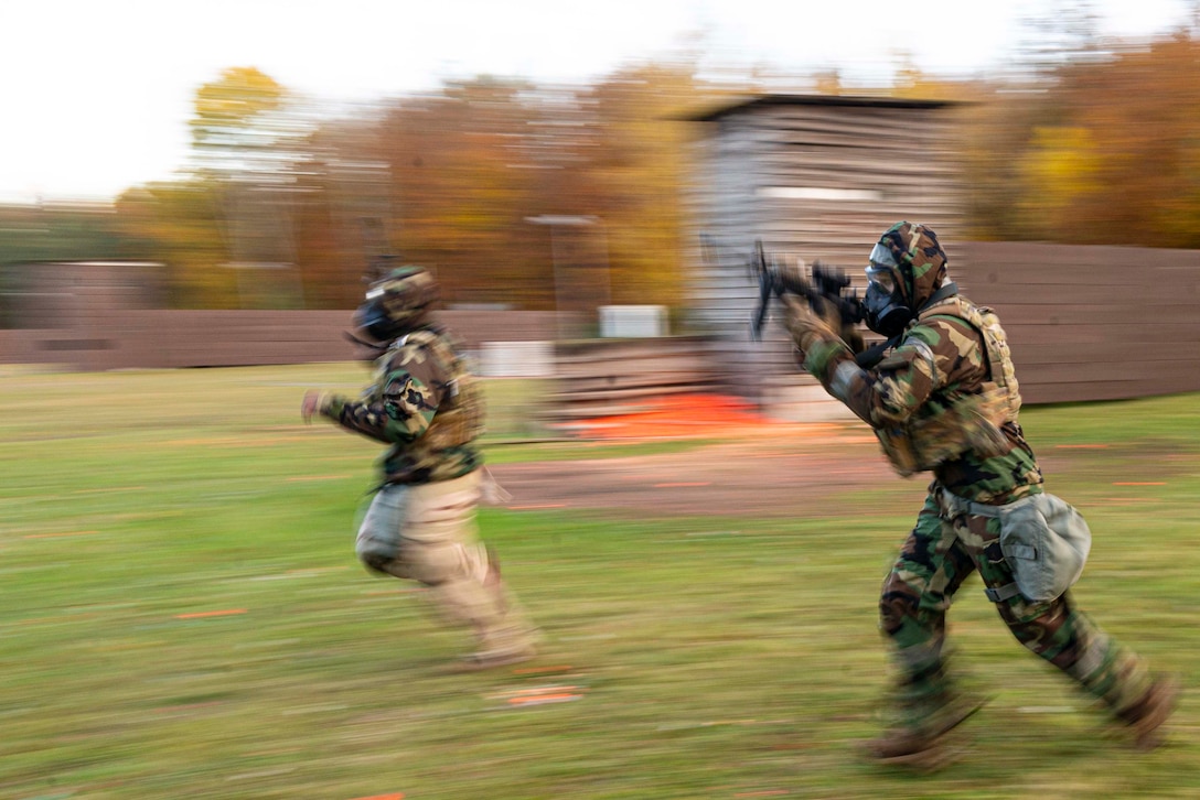 Two airmen run while holding weapons.