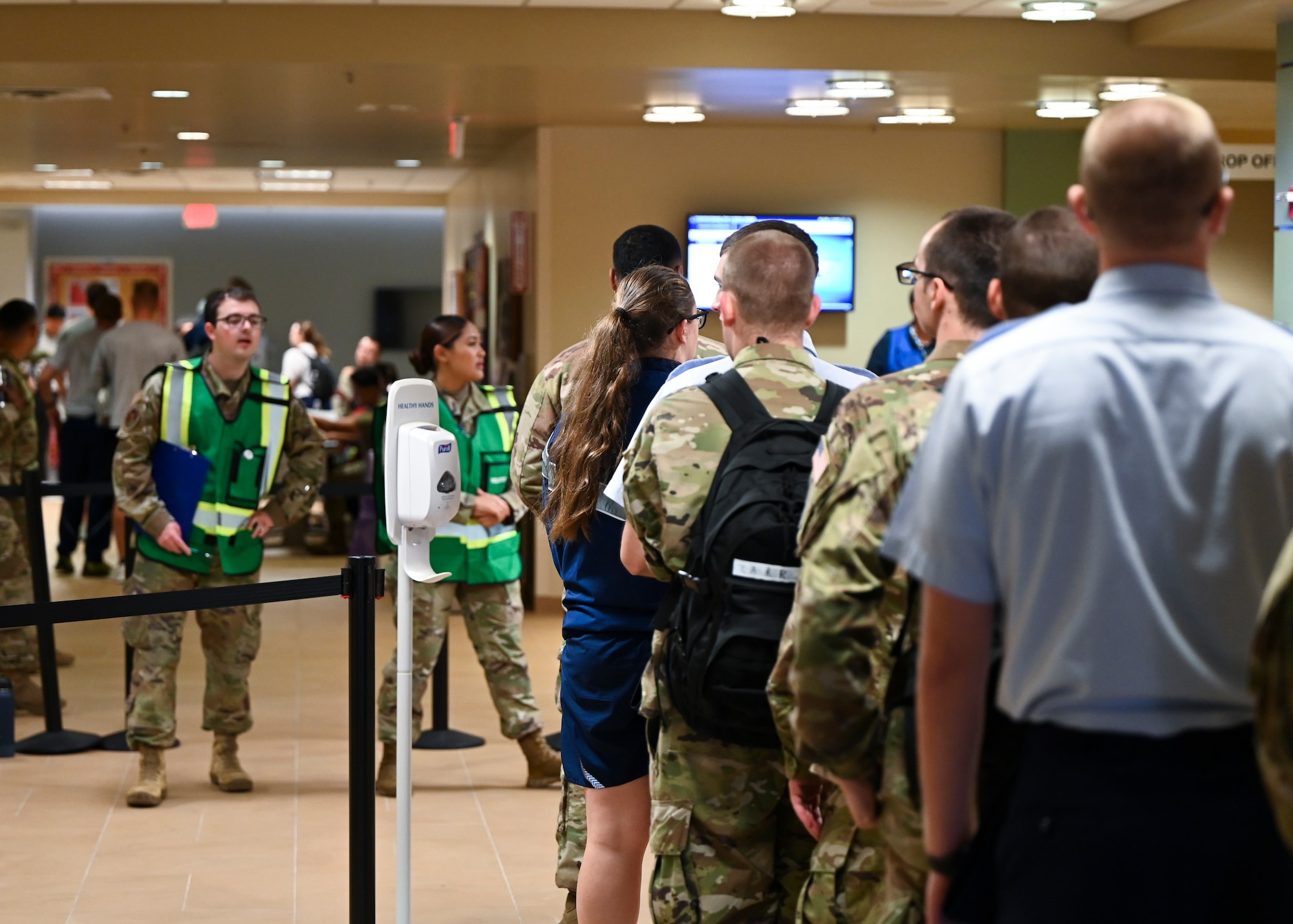 People form a line inside the hospital, waiting to be called by medical staff.