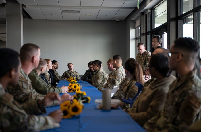U.S. and Ukrainian military members sit at a table with flowers on it