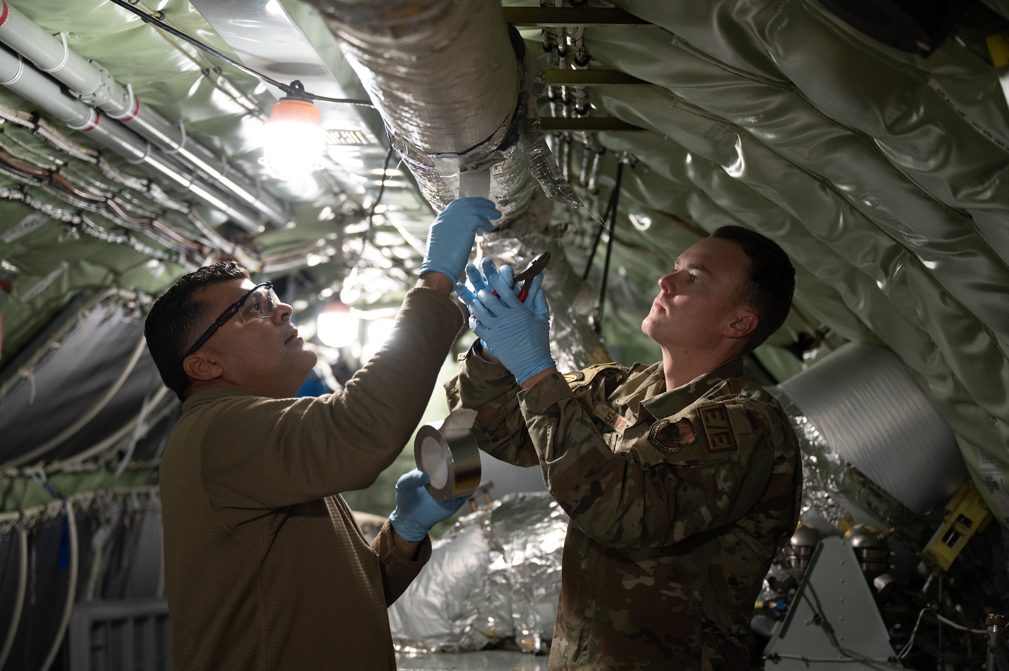 Master Sgt. Ramon Ortiz, 459th Maintenance Squadron aircraft electrical and environmental systems technician, and Tech. Sgt. Ryan Saylor, 434th Maintenance Squadron environmental systems technician, install insulation on the delivery vents of a KC-135R Stratotanker’s auxiliary power unit at Grissom Air Reserve Base, Ind., Nov. 8, 2023.