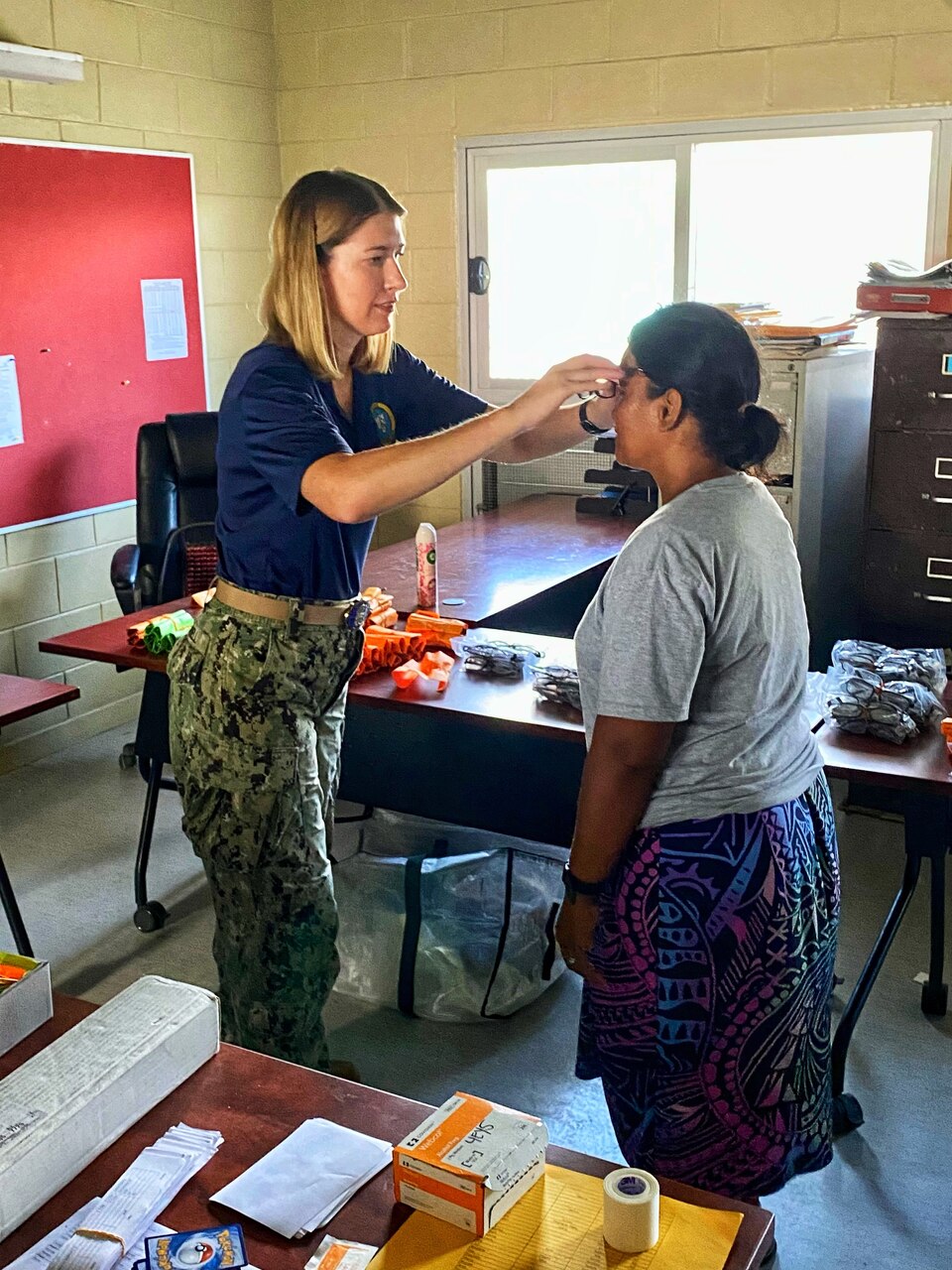 U.S. Navy Cdr. Mary Beth Linnell, optometrist, fits a woman on Ebeye for new glasses following her eye exam. Linnell and her Sailors were providing two days of dental, optometry and cardiology services on Ebeye, part of Pacific Partnership.