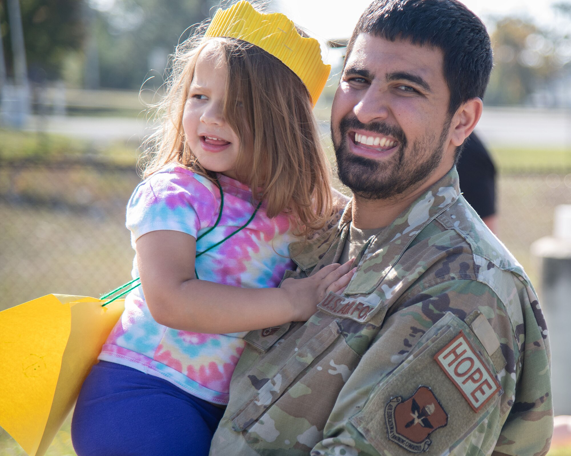 An Airman carries his daughter during a parade.