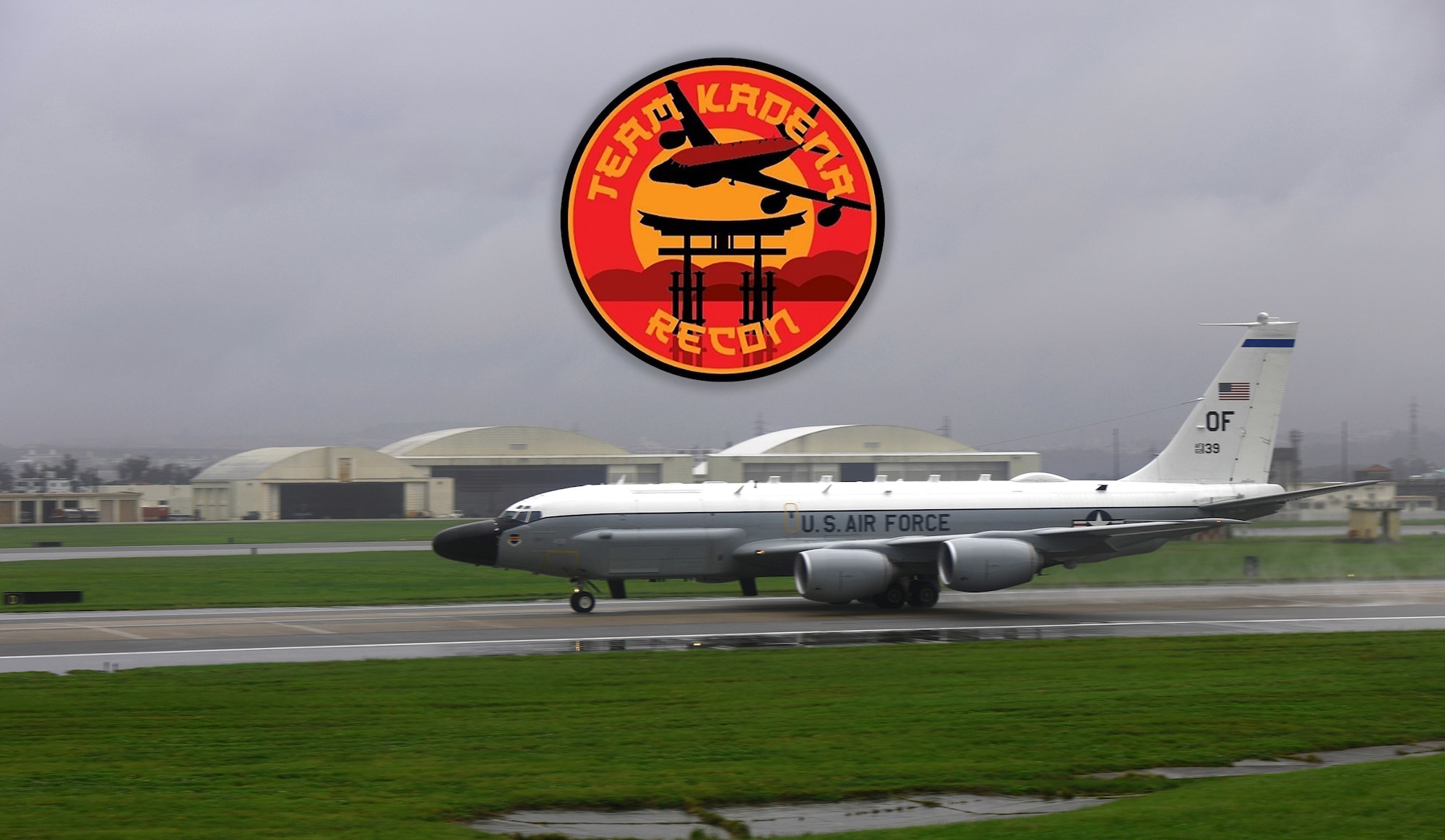 Orange and yellow logo placed overhead of photo with aircraft landing in rainy conditions.