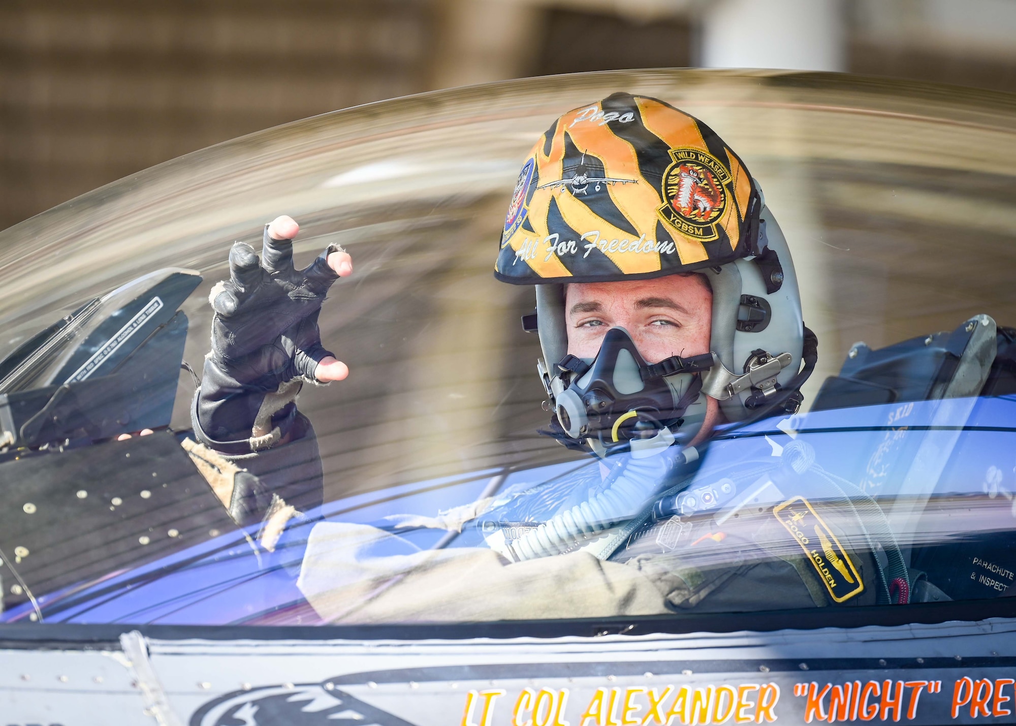 A pilot displays his squadrons signature tiger claw hand signal in the cockpit of an F-16.