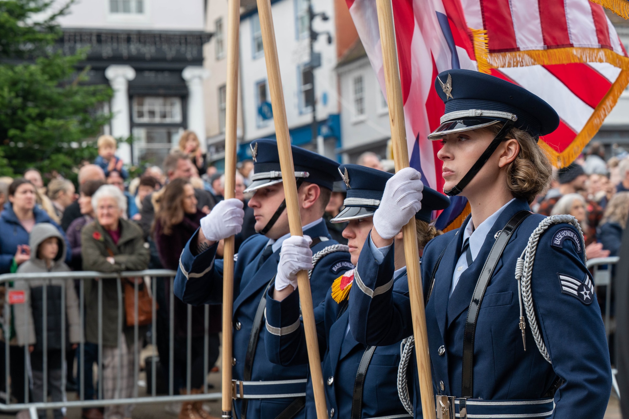 3 people march in a parade holding flags