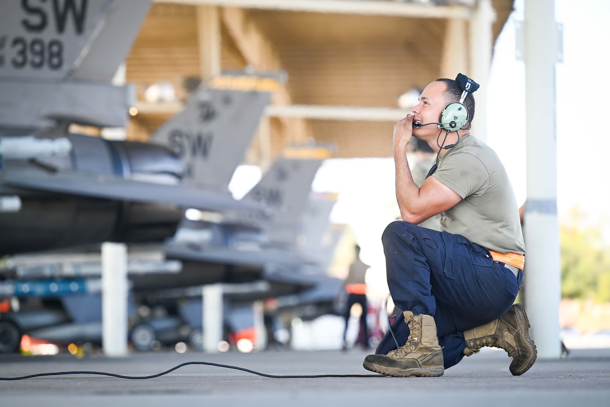 An crew chief kneels while performing pre-flight checks.