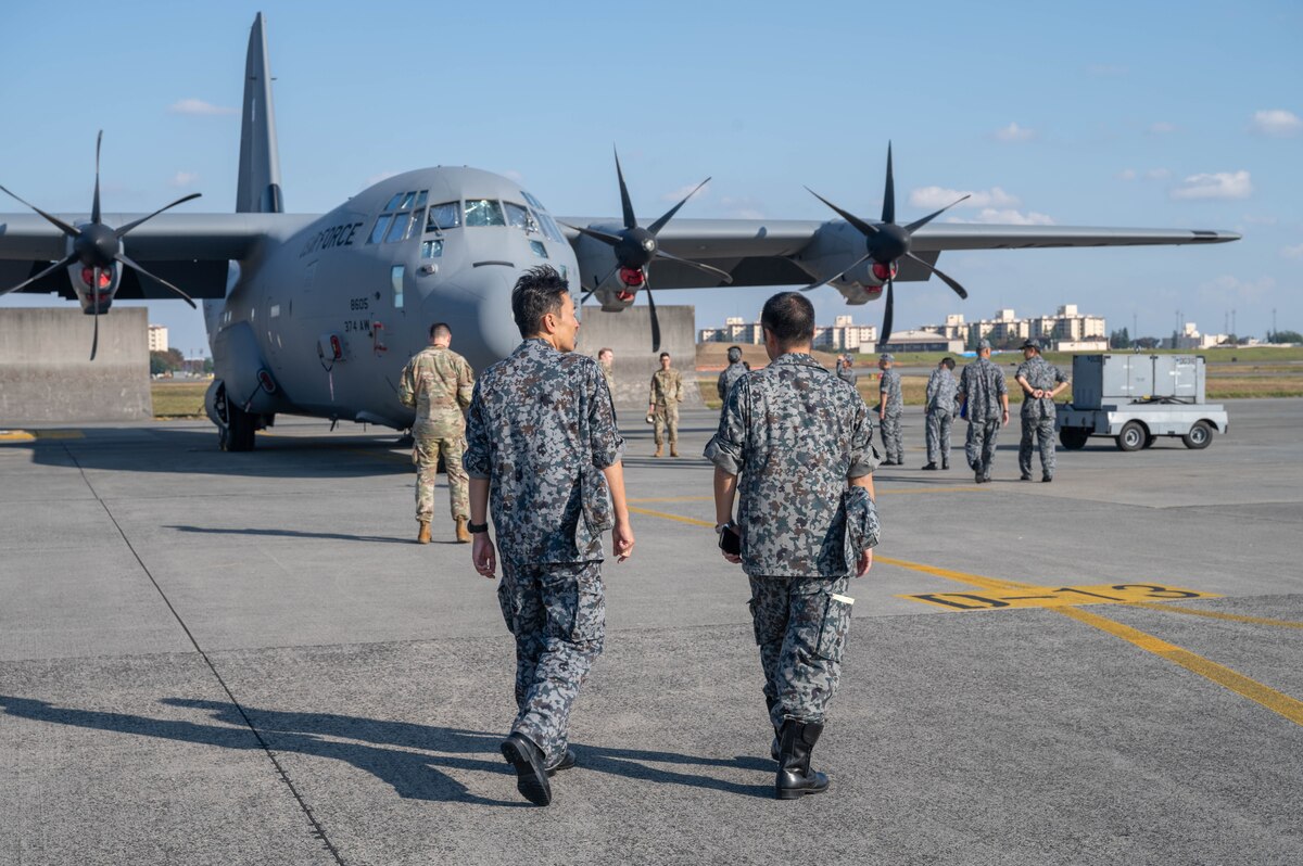Two people in uniform are in the photo. They are walking towards an aircraft.