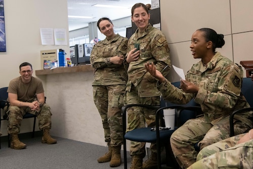 A group of military members talk to each other during a team-building activity.