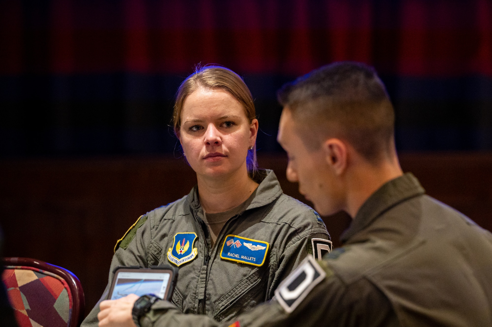 U.S. Air Force Capt. Rachel Mallets, left, 100th Operations Support Squadron KC-135 Stratotanker pilot, and Capt. Anthony Vecchio, right, 100th OSS KC-135 Stratotanker pilot, speak to NATO allies about the capabilities of the KC-135 during the European Tanker Symposium at Royal Air Force Mildenhall, England, Nov. 16, 2023.