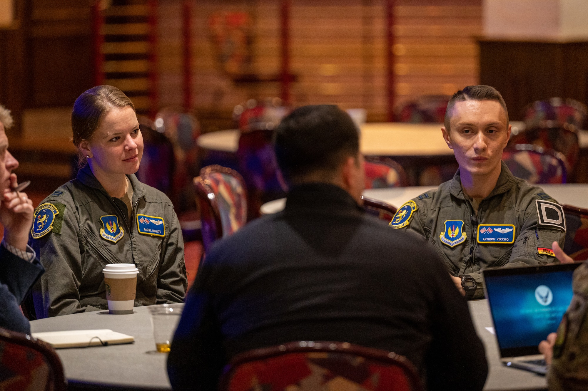 U.S. Air Force Capt. Rachel Mallets, left, 100th Operations Support Squadron KC-135 Stratotanker pilot, and Capt. Anthony Vecchio, right, 100th OSS KC-135 Stratotanker pilot, speak to NATO allies about the capabilities of the KC-135 during the European Tanker Symposium at Royal Air Force Mildenhall, England, Nov. 16, 2023.