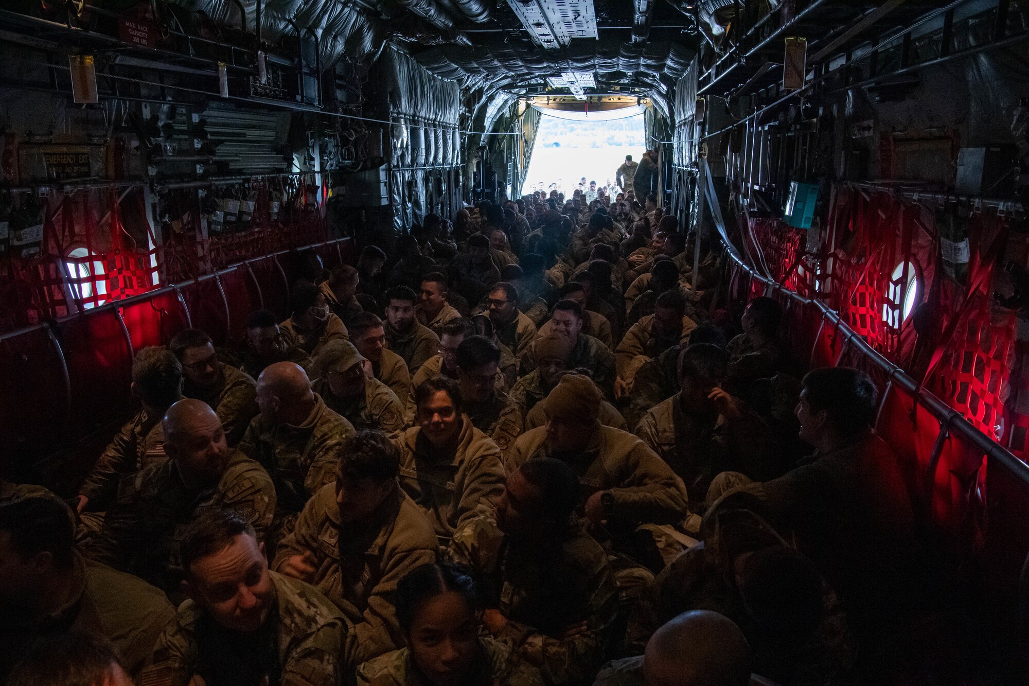 U.S. Air Force Airmen assigned to the 37th Airlift Squadron, as well as deployed Airmen assigned to the 621st Contingency Response Wing, Travis Air Force Base, California, and Quonset Point Air National Guard Station, Rhode Island, participate as mock passengers onboard a static C-130J Super Hercules aircraft during floor-loading training at Ramstein Air Base, Germany, Nov. 9, 2023. The 37th AS held this training event to rehearse floor-loading procedures used primarily in contingency operations and humanitarian aid missions, during which the maximum number of passengers are loaded onto an aircraft without the standard use of seatbelts or stanchions. (U.S. Air Force photo by Senior Airman Jared Lovett)