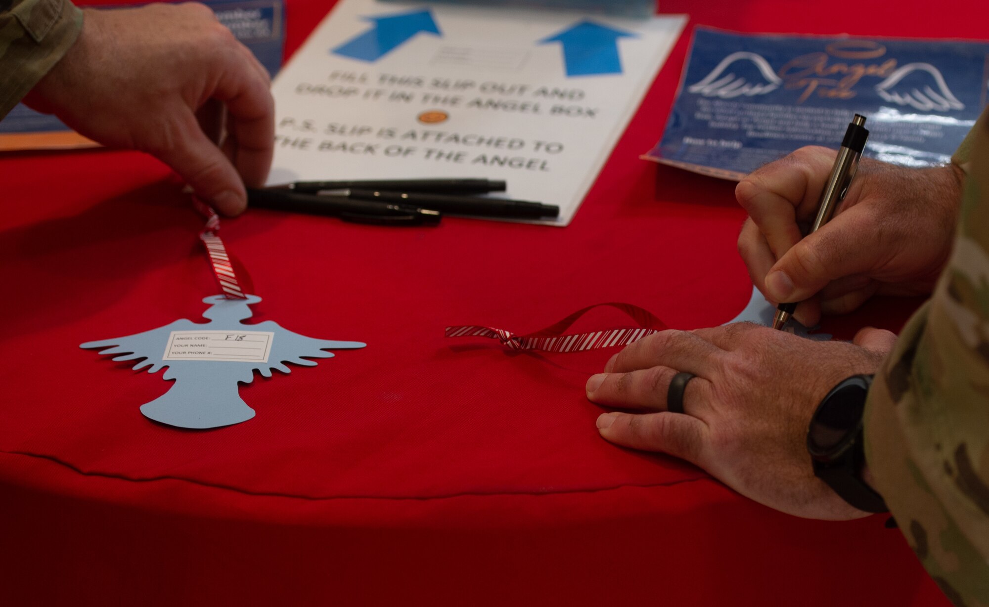U.S. Air Force Airmen from the 23rd Wing fill out angel tags at Moody Air Force Base, Georgia, Nov. 17, 2023. The angel shaped tags are from the Angel tree, which is a program where Airmen from base take the information from the cards and buy gifts for children of Team Moody. (U.S. Air Force photo Airman Cade Ellis)