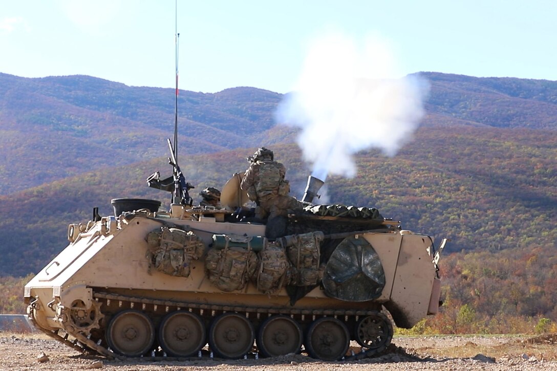 Soldiers fire mortars from a tank.