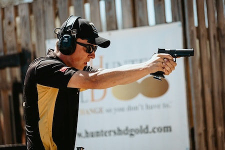 Man in Army Polo shooting pistol.