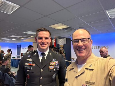Two men in military uniforms pose together at a conference