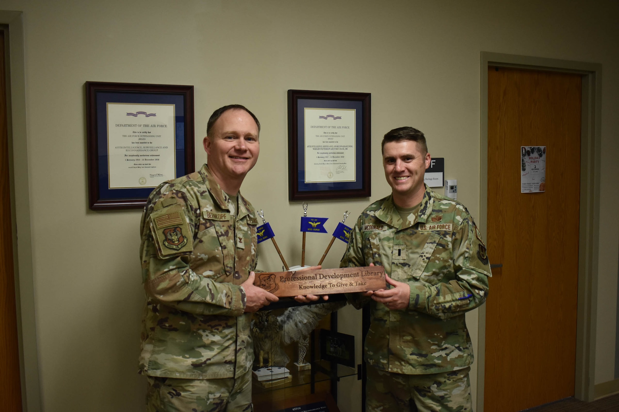 Col. Eric Bernkopf (left), 655th Intelligence, Surveillance and Reconnaissance (ISR) Group commander, presents a wood plank to 1st Lt. Matt McDonald, 88th Air Base Wing assistant staff judge advocate and an original member of the 655th ISRG when it stood up in 2013, during a short ceremony Nov. 3, 2023, at the 655th ISR Wing headquarters. The group named 16 members as plank holders when the group officially stood up in September 2013.