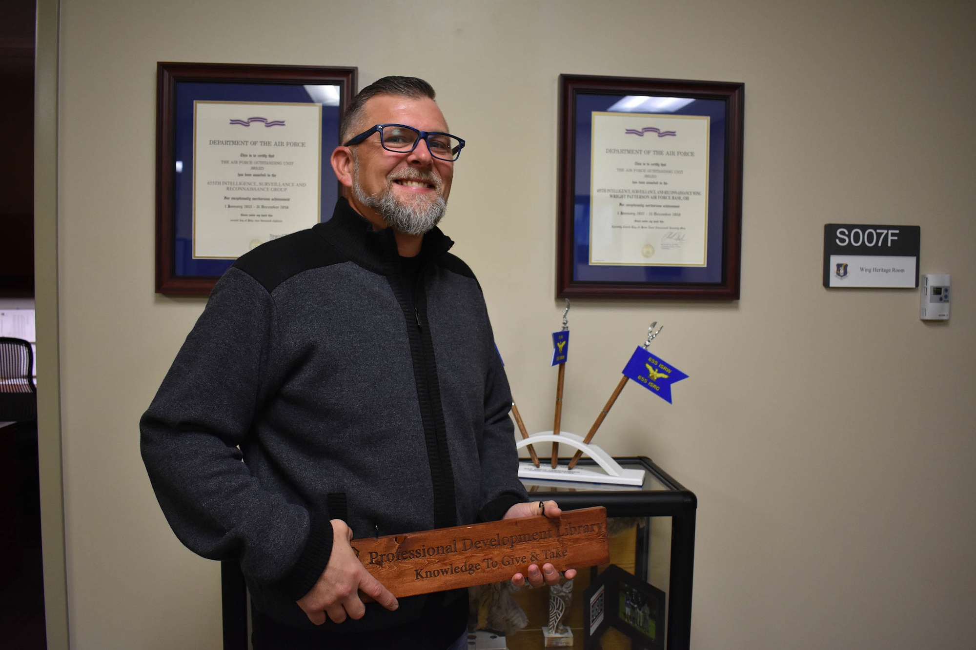 Retired Master Sgt. Todd Cook, civilian personnel liaison for the 655th Intelligence, Surveillance and Reconnaissance (ISR) Wing and an original member of the 655th ISR Group when it stood up in 2013, is presented with a wood plank on Nov. 14, 2023, at the 655th ISR Wing headquarters. The group named 16 members as plank holders when the group officially stood up in September 2013.