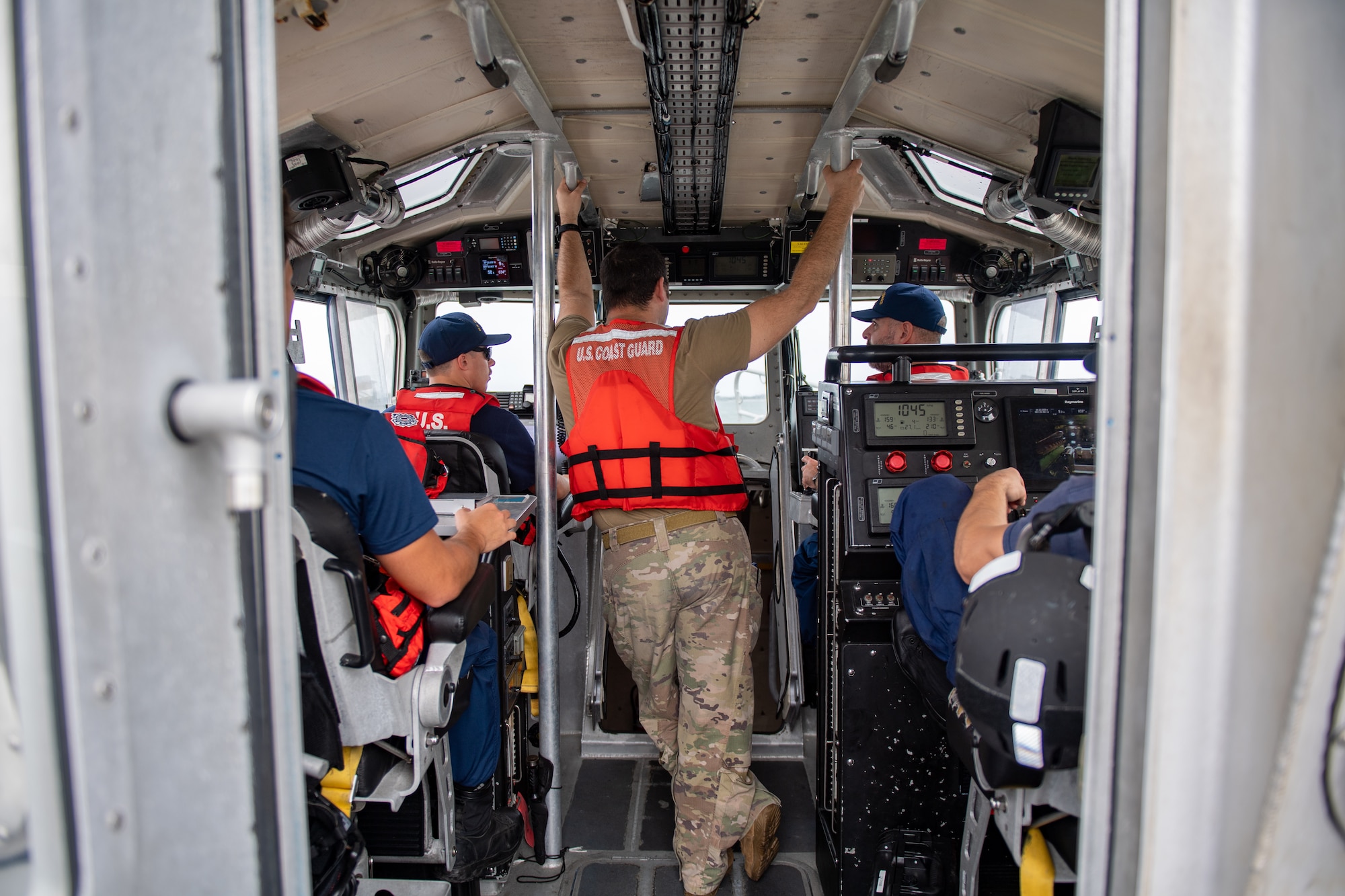 U.S. Air Force Tech. Sgt. Michael Mendes, 347th Operations Support Squadron group weapons and tactics load master, listens to U.S. Coast Guardsmen during a simulated joint team exercise in the Saint Johns River in Jacksonville on Nov. 17, 2023. The Air Force rescue community's mission objective of conducting search and rescue, combined with the Coast Guard's commitment to ensuring maritime safety, merged in an effort to assess how joint team concepts can merge during water rescues. (U.S. Air Force photo by Senior Airman Courtney Sebastianelli)