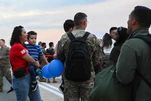 Adults holding children talk with one another.