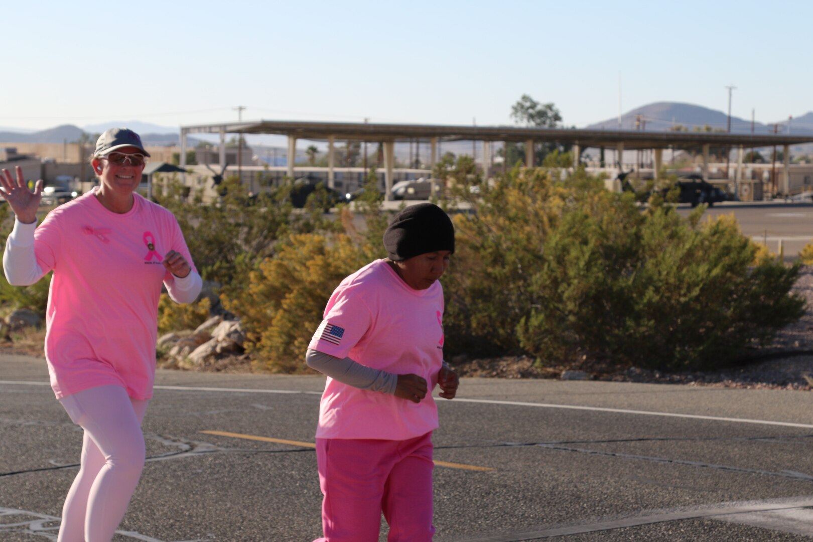 Two women wearing pink running up a street.