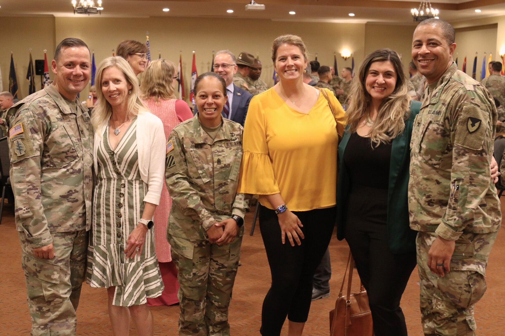 Army members in uniform and spouses posing for a picture.