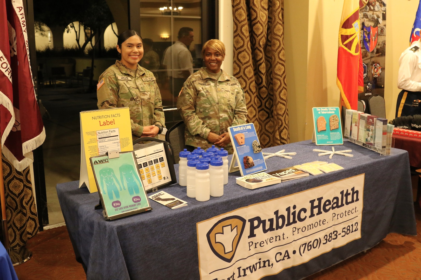 Two US Army soldiers host an informational booth at community event.