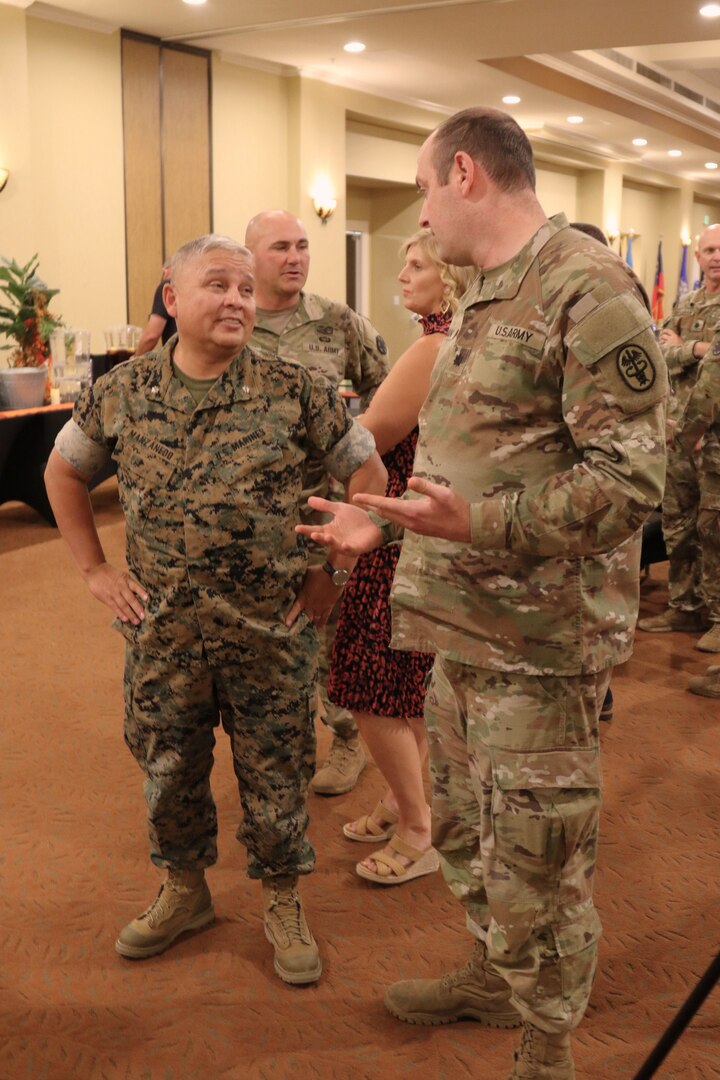 A marine and soldier speaking to each other while standing up.