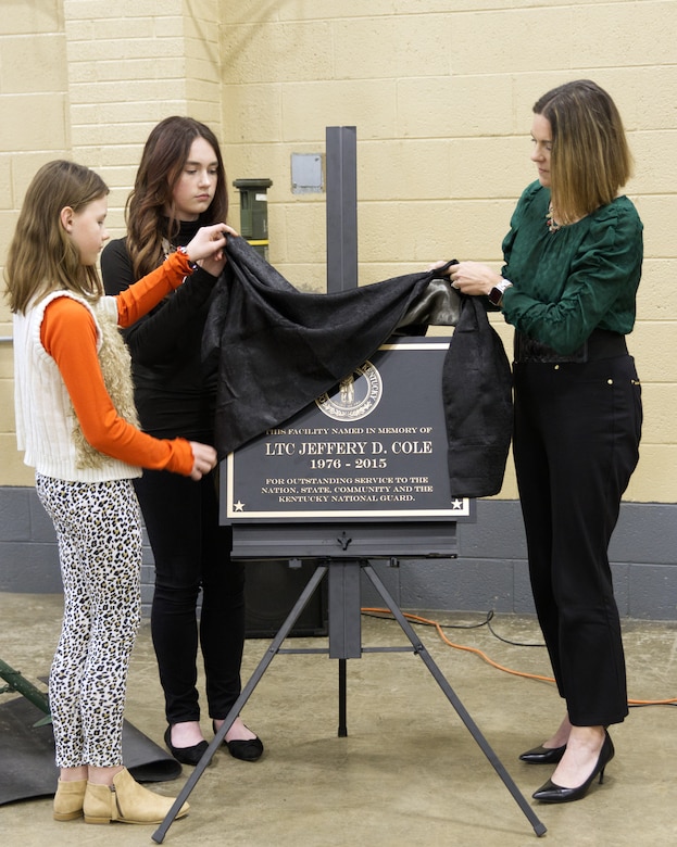 Christi Cole Pope and daughters Abrienna and Emmery unveil a plaque during an armory naming ceremony in Middlesboro, Kentucky, Nov. 17, 2023.
