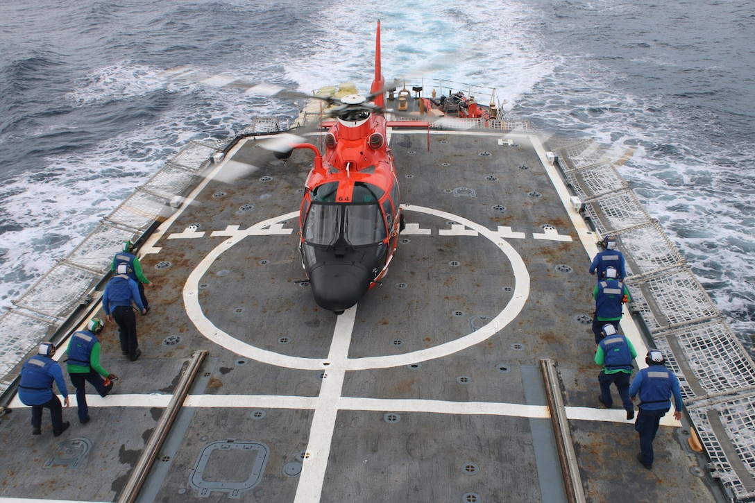 A helicopter tie-down crew from the U.S. Coast Guard Cutter Escanaba (WMEC 907) approaches an MH-65 helicopter from the U.S. Coast Guard Helicopter Interdiction Tactical Squadron during a patrol in the Eastern Pacific Ocean, Oct. 16, 2023. Escanaba’s crew disrupted illegal narcotics smuggling, interdicting 3,520 kilograms of cocaine valued at more than $102 million, which were offloaded in Port Everglades, Florida.