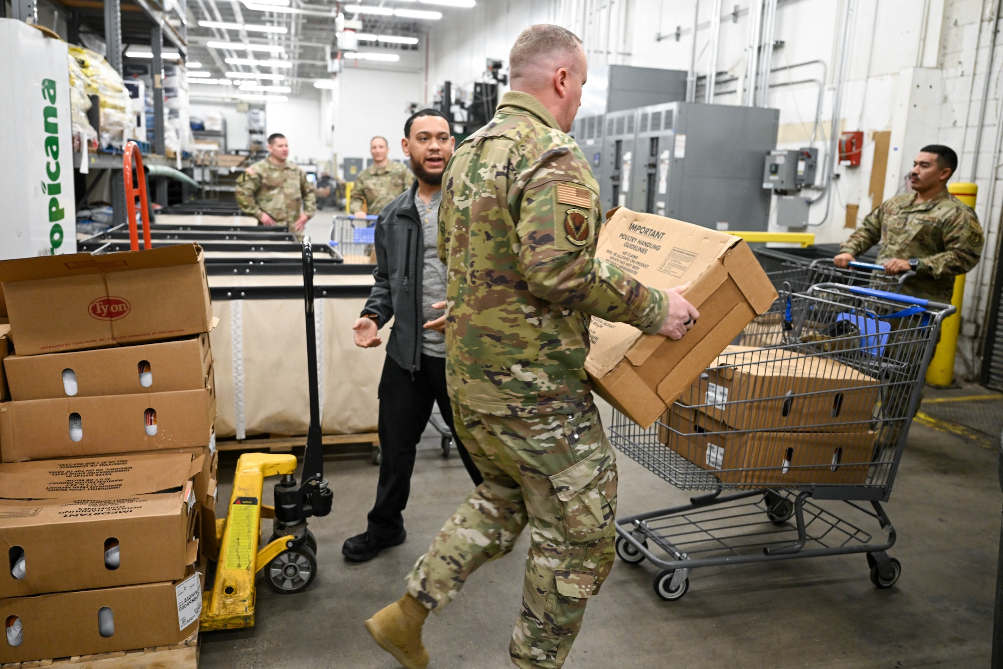 A first sergeant loads a box of turkeys into a grocery cart.