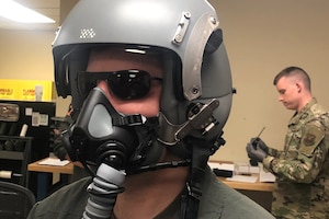 An airman wears a mask and head and eye protection.