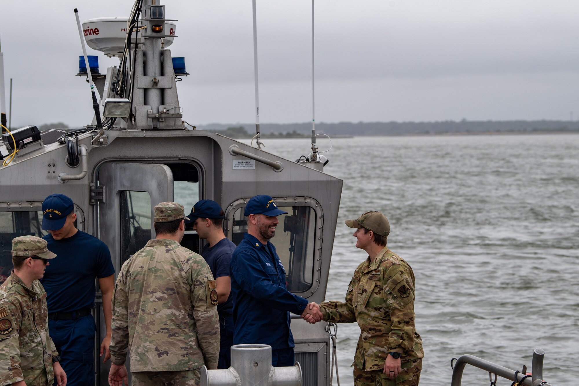 U.S. Coast Guardsman greet U.S. Air Force Airmen assigned to the 347th Operations Support Squadron during Mosaic Tiger 24-1 off the coast of Jacksonville on Nov. 17, 2023. Joint team training exercises ensure both branches are prepared for global maritime personnel recovery. (U.S. Air Force photo by Senior Airman Courtney Sebastianelli)