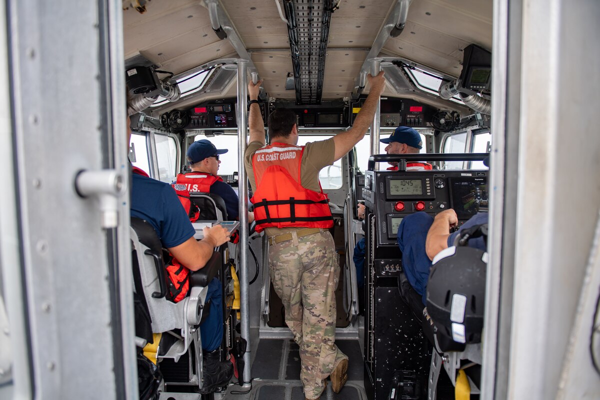 U.S. Air Force Tech. Sgt. Michael Mendes, 347th Operations Support Squadron group weapons and tactics load master, listens to U.S. Coast Guardsmen during a simulated joint team exercise in the Saint Johns River in Jacksonville on Nov. 17, 2023. The Air Force rescue community's mission objective of conducting search and rescue, combined with the Coast Guard's commitment to ensuring maritime safety, merged in an effort to assess how joint team concepts can merge during water rescues. (U.S. Air Force photo by Senior Airman Courtney Sebastianelli)