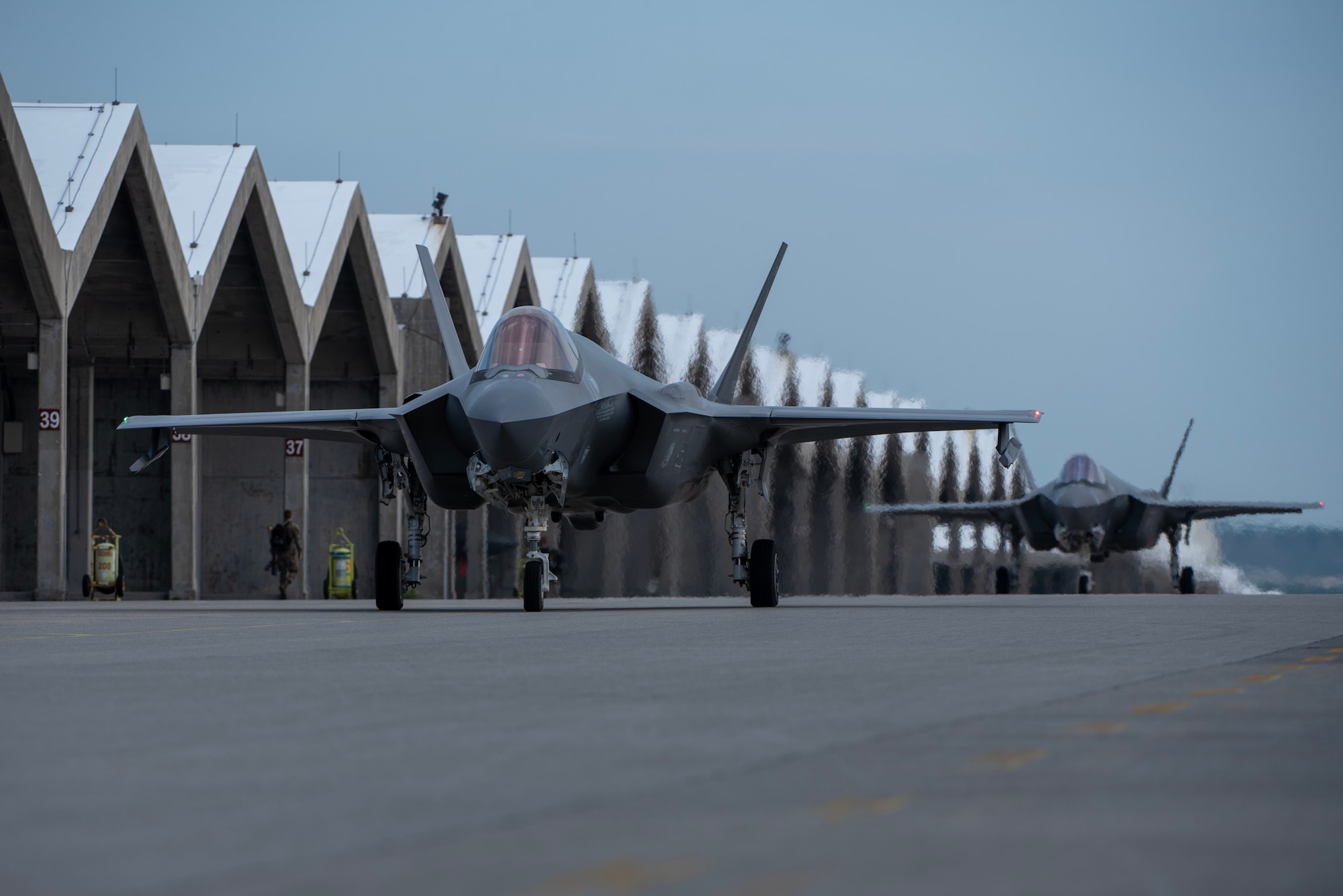 two fighter plans drive away from their hangars