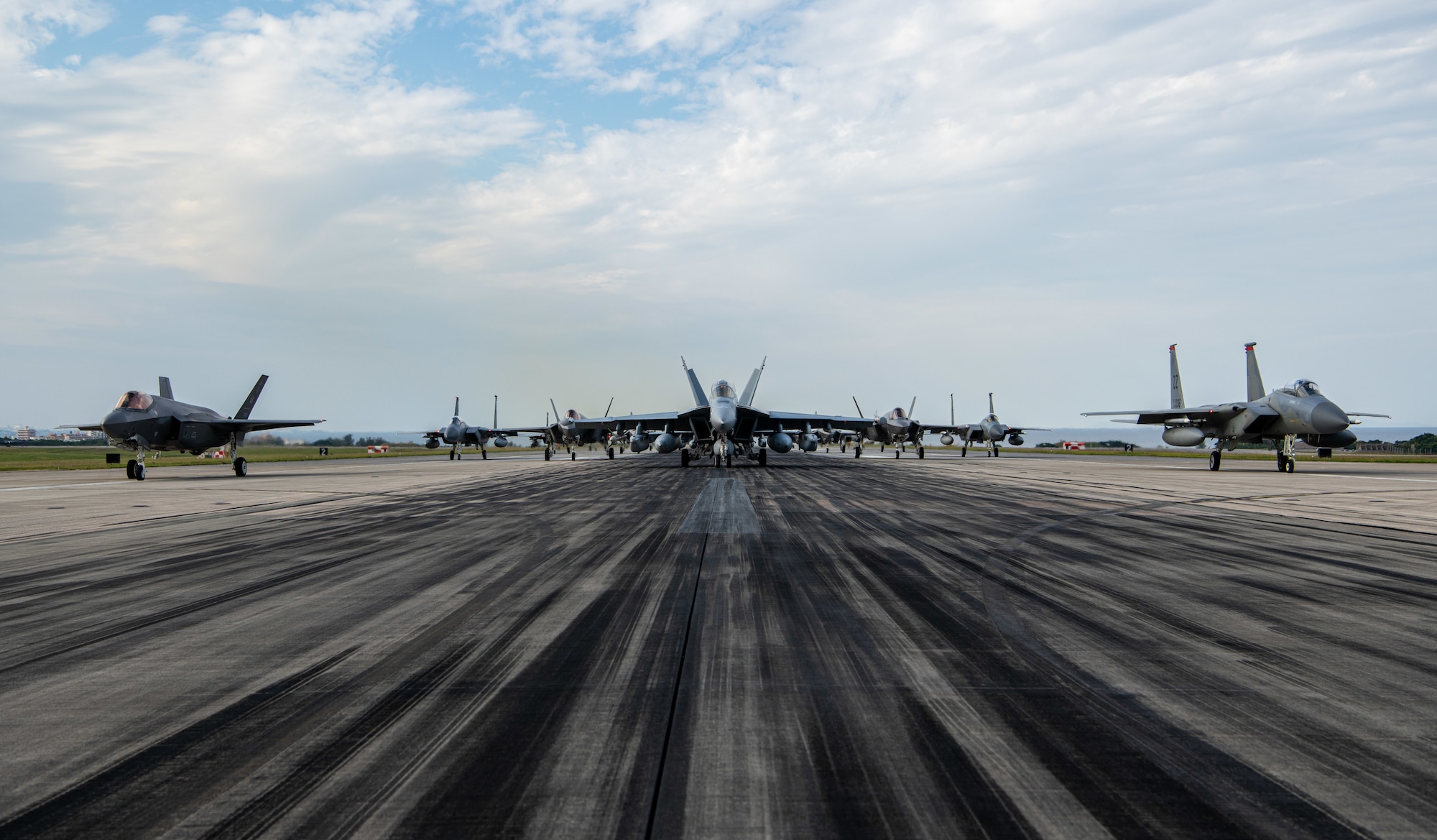 Fighter jets pose on a runway.