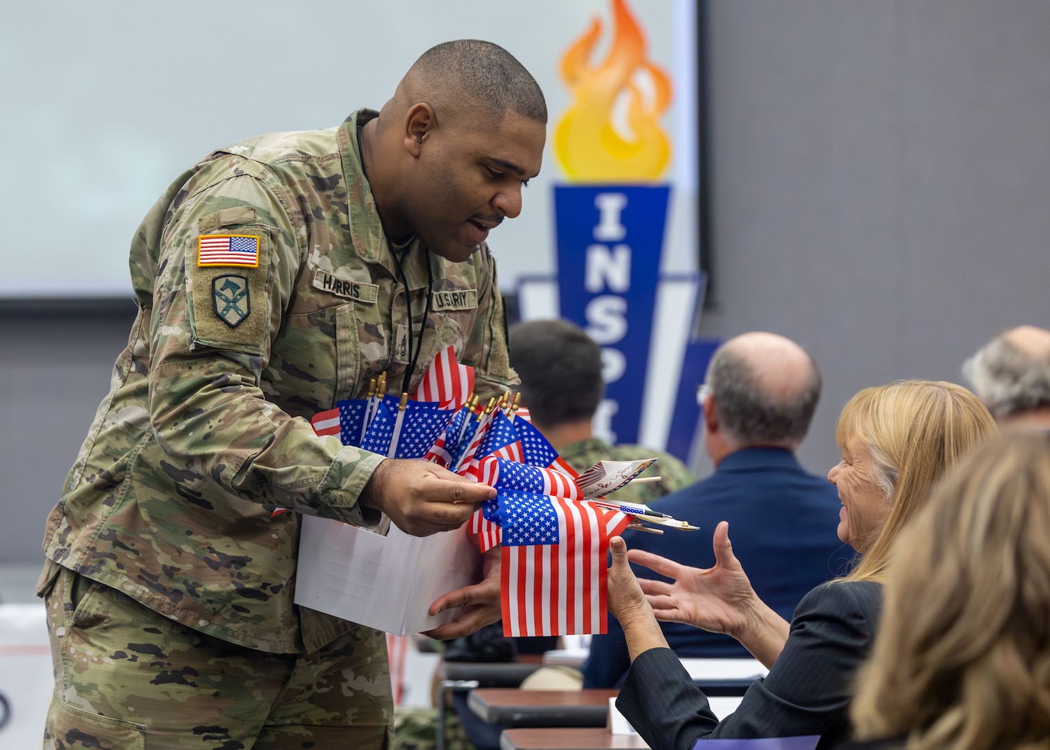 Sergeant First Class Johnny Alphonso Harris, Naval Surface Warfare Center Panama City Division Equal Employment Opportunity and Diversity & Inclusion (ED&I) specialist, hands out American flags to INSPIRE 2.0 attendees, Nov. 14. The event began by recognizing the civilian workforce who actively serve in the military, is a military veteran, is a family member of a military member or those who took the oath of federal service who support this country and its servicemembers. (U.S. Navy photo by Eddie Green)