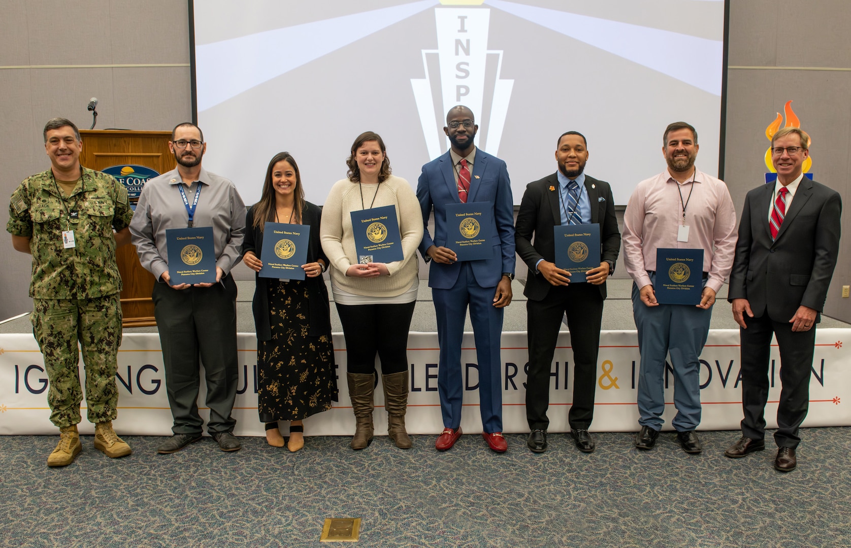 (left and right) Capt. David Back, Naval Surface Warfare Center Panama City Division (NSWC PCD) commanding officer, and Dr. Peter Adair, NSWC PCD technical director, recognize six NSWC PCD personnel at INSPIRE 2.0 who received certificates for their efforts in serving as fiscal year 2023 special emphasis program (SEP) leads, Nov. 14. NSWC PCD's SEP exists to help the workforce develop, network, connect and participate in groups to strengthen the command. (U.S. Navy photo by Eddie Green)