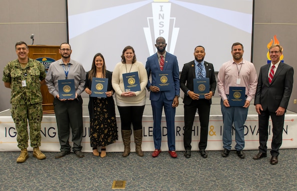 (left and right) Capt. David Back, Naval Surface Warfare Center Panama City Division (NSWC PCD) commanding officer, and Dr. Peter Adair, NSWC PCD technical director, recognize six NSWC PCD personnel at INSPIRE 2.0 who received certificates for their efforts in serving as fiscal year 2023 special emphasis program (SEP) leads, Nov. 14. NSWC PCD's SEP exists to help the workforce develop, network, connect and participate in groups to strengthen the command. (U.S. Navy photo by Eddie Green)